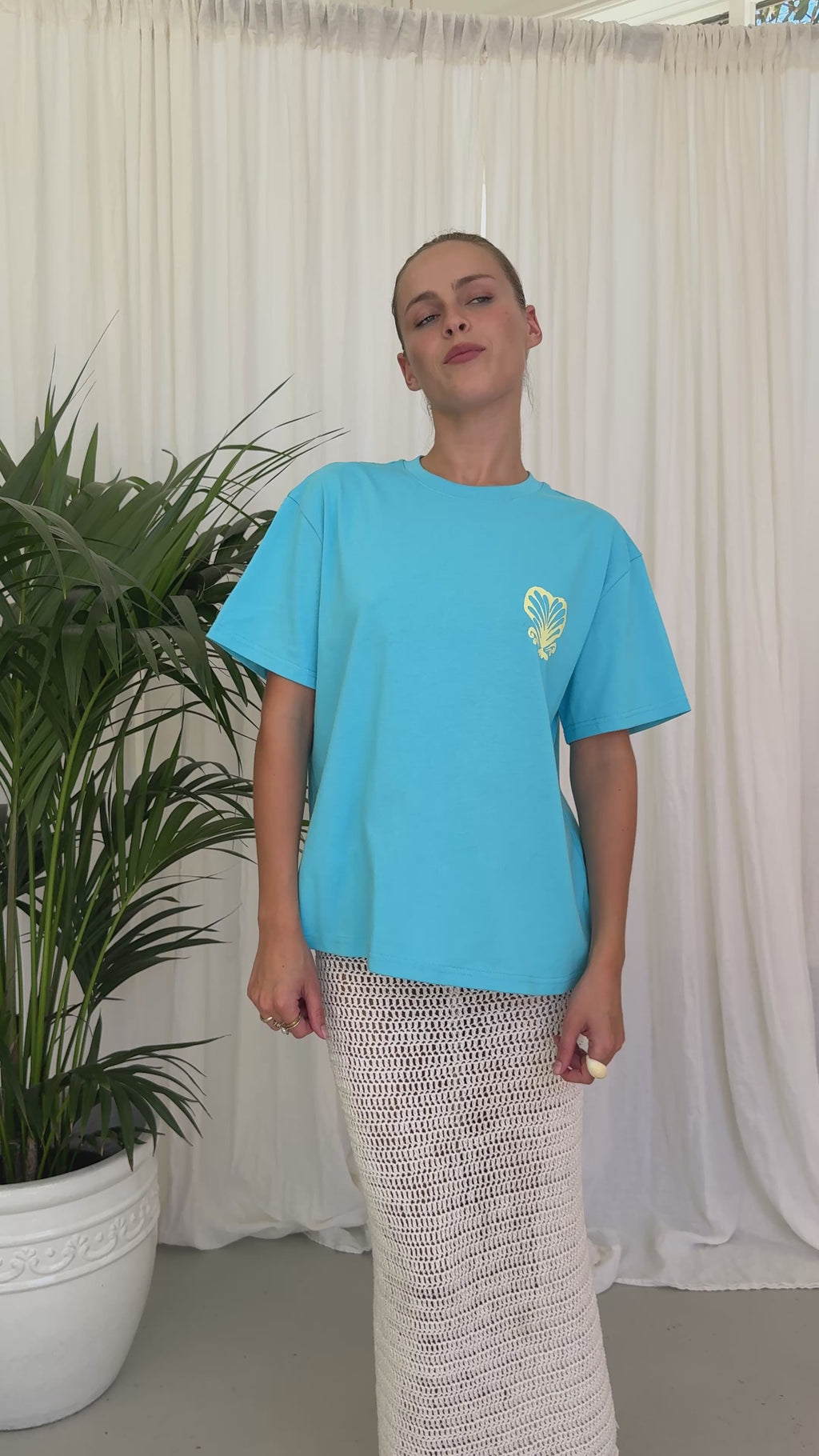 Blue T-shirt BELLARUCHI. Blue T-shirt with shell. Blue t-shirt yellow writing. Blue tshirt yellow back logo. BELLARUCHI Blue tee. Boxy Blue tee. Aqua Boxy Tee. Aqua Tee. 